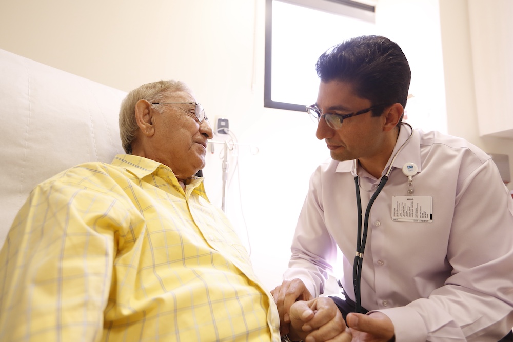 Photo of a male participant in a collared shirt speaking quietly with a doctor at Brandman.