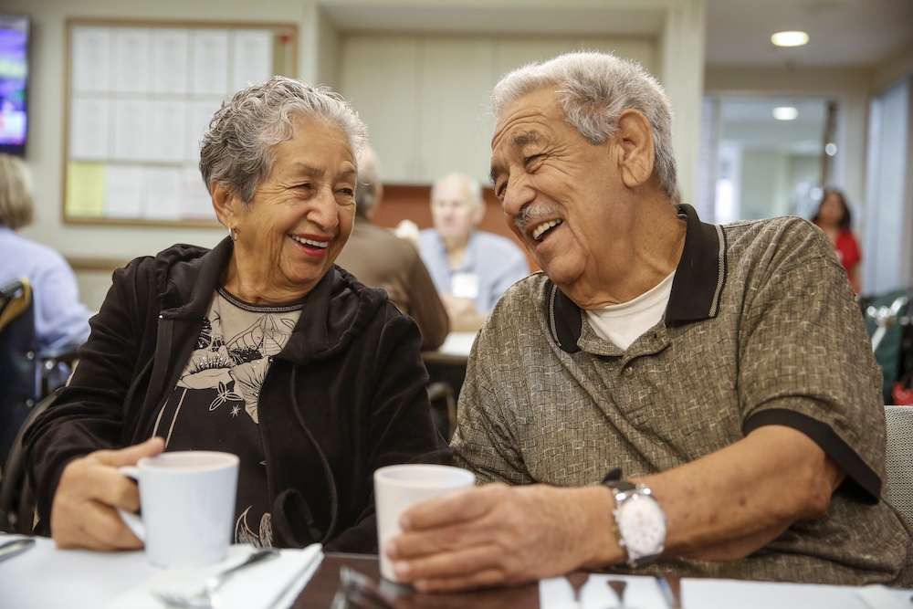 Photo of a Man and woman share a laugh over a cup of coffee.